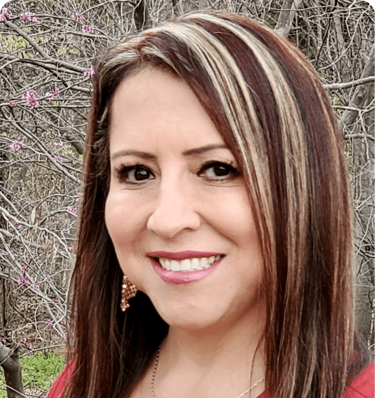 Smiling woman with highlighted hair outdoors.