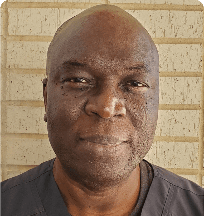Man smiling against brick wall background.