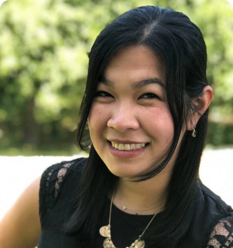 Woman in black top smiling outside.